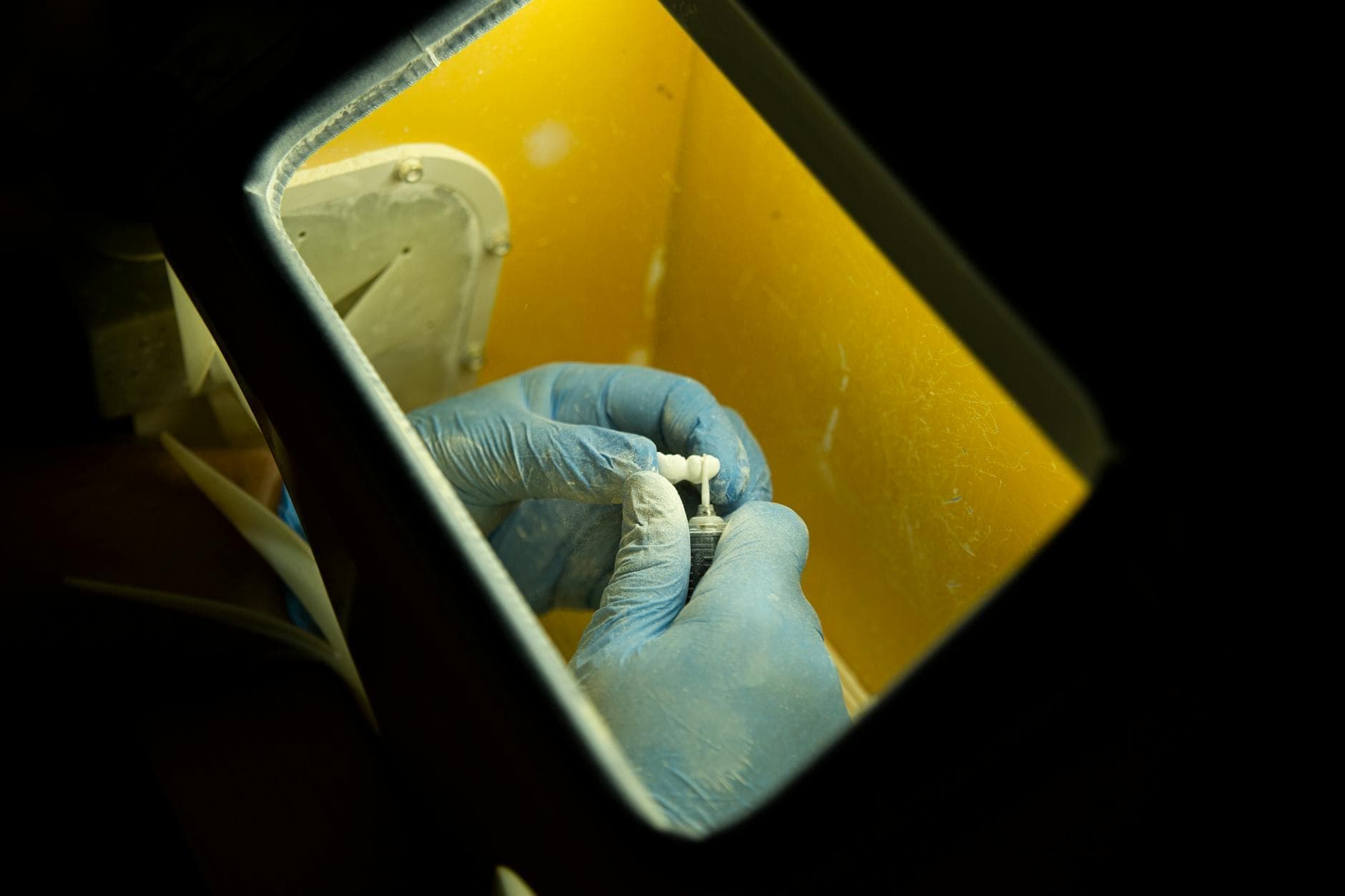 A technician finishing a zirconia bridge in the laboratory.